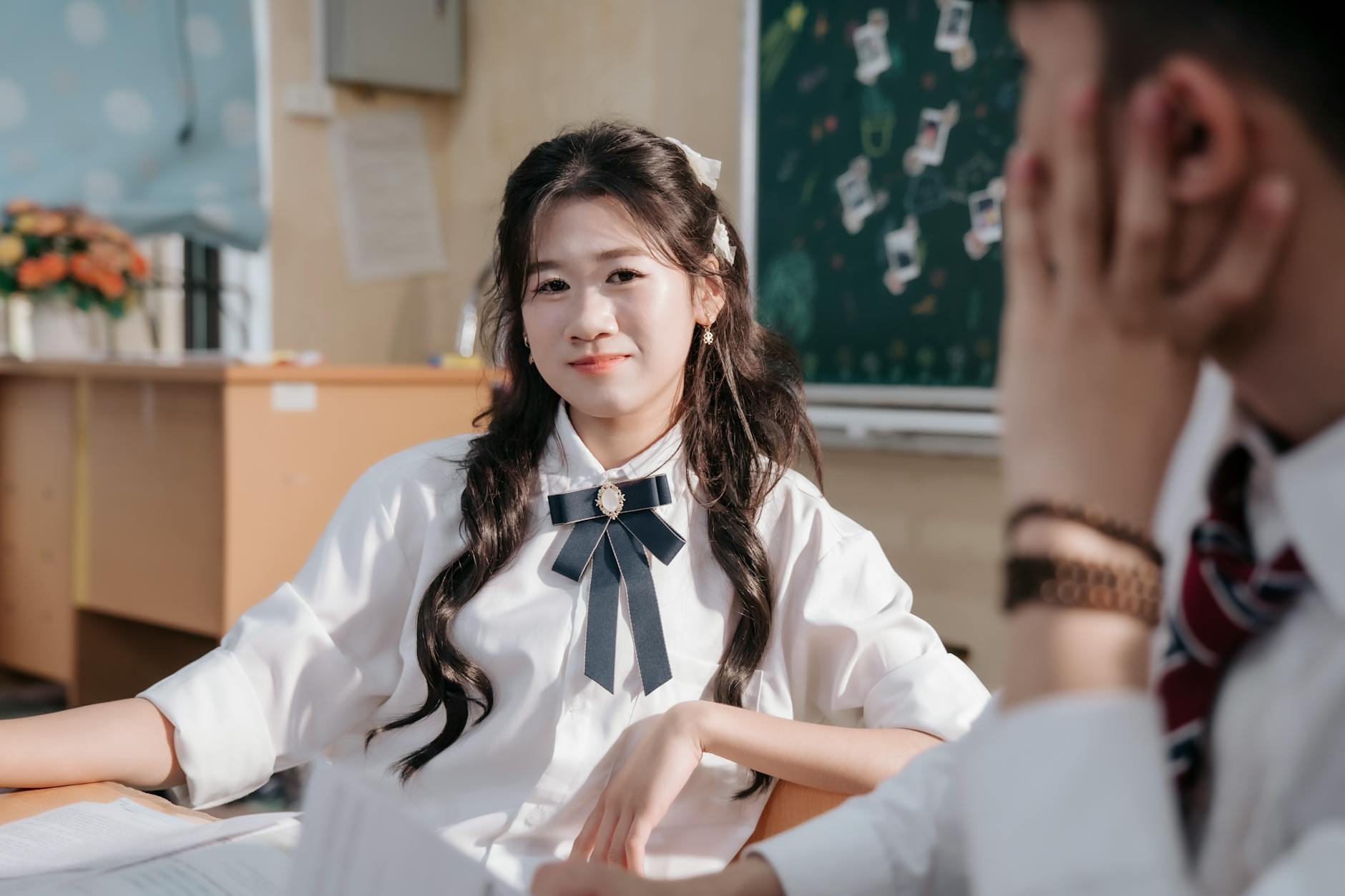 Uśmiechnięci licealiści siedzący w klasie na tle tablicy