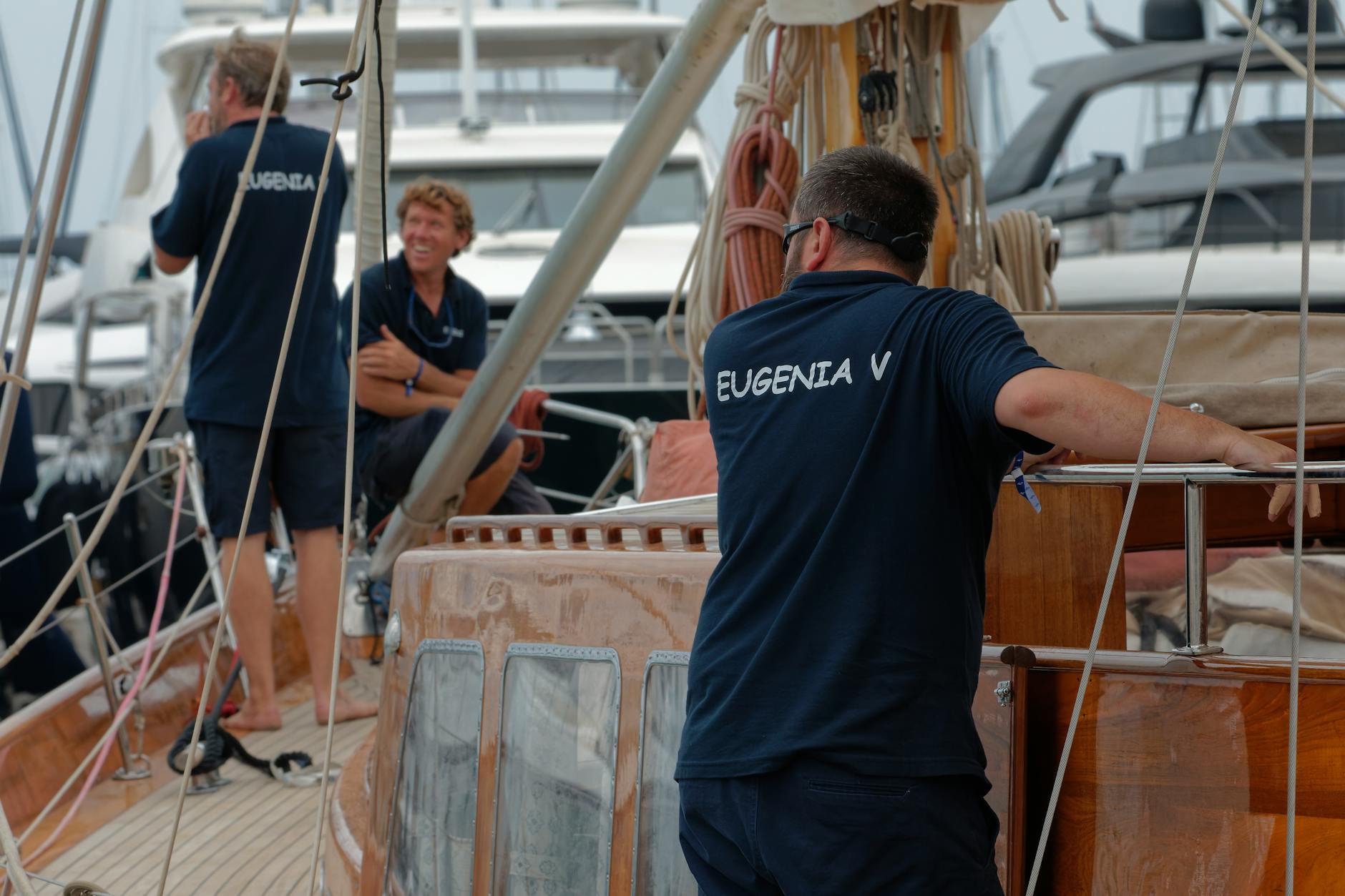 Dorośli szykują jacht do wypłynięcia w ruchliwym porcie