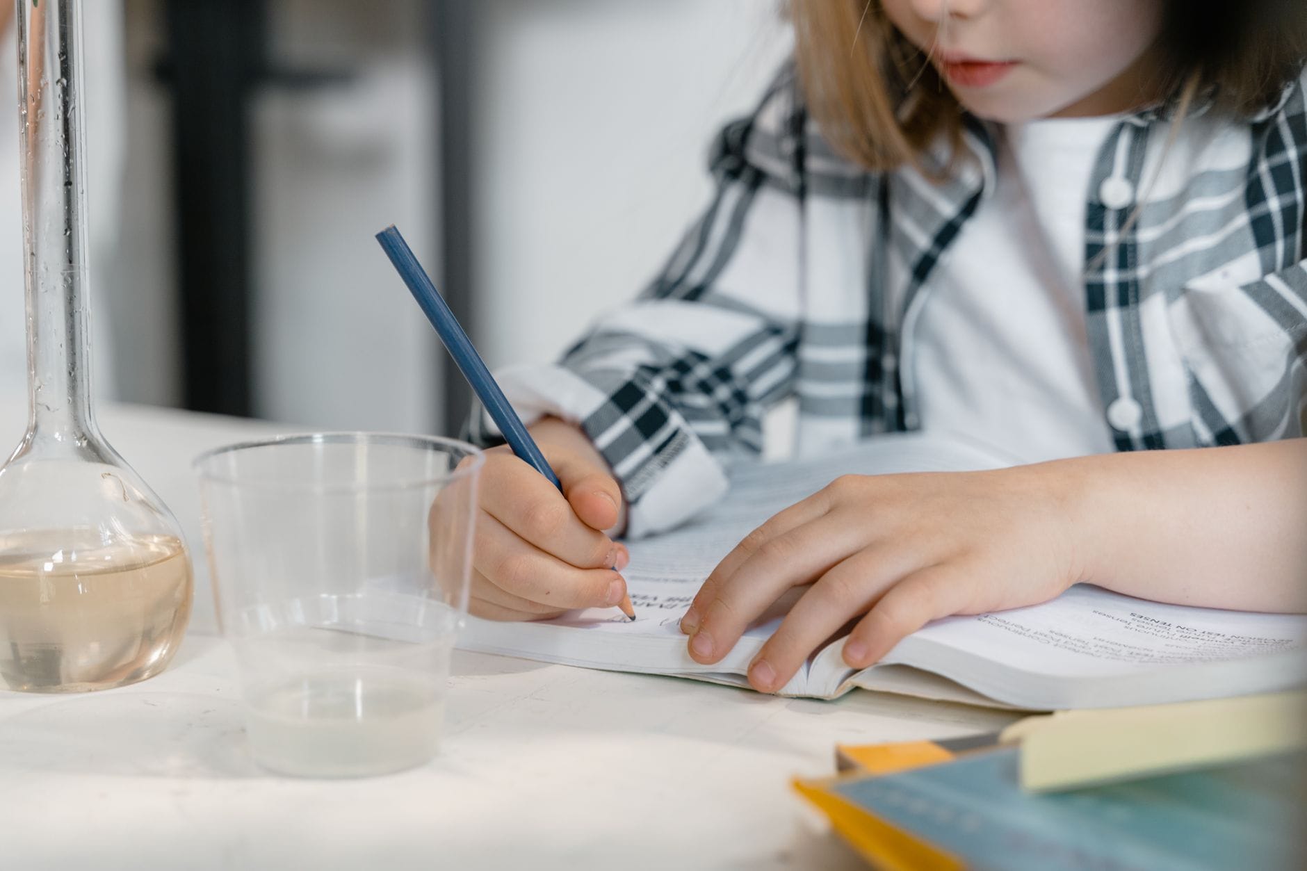 Dziecko uczy się chemii przy książkach i laboratoryjnej zlewce