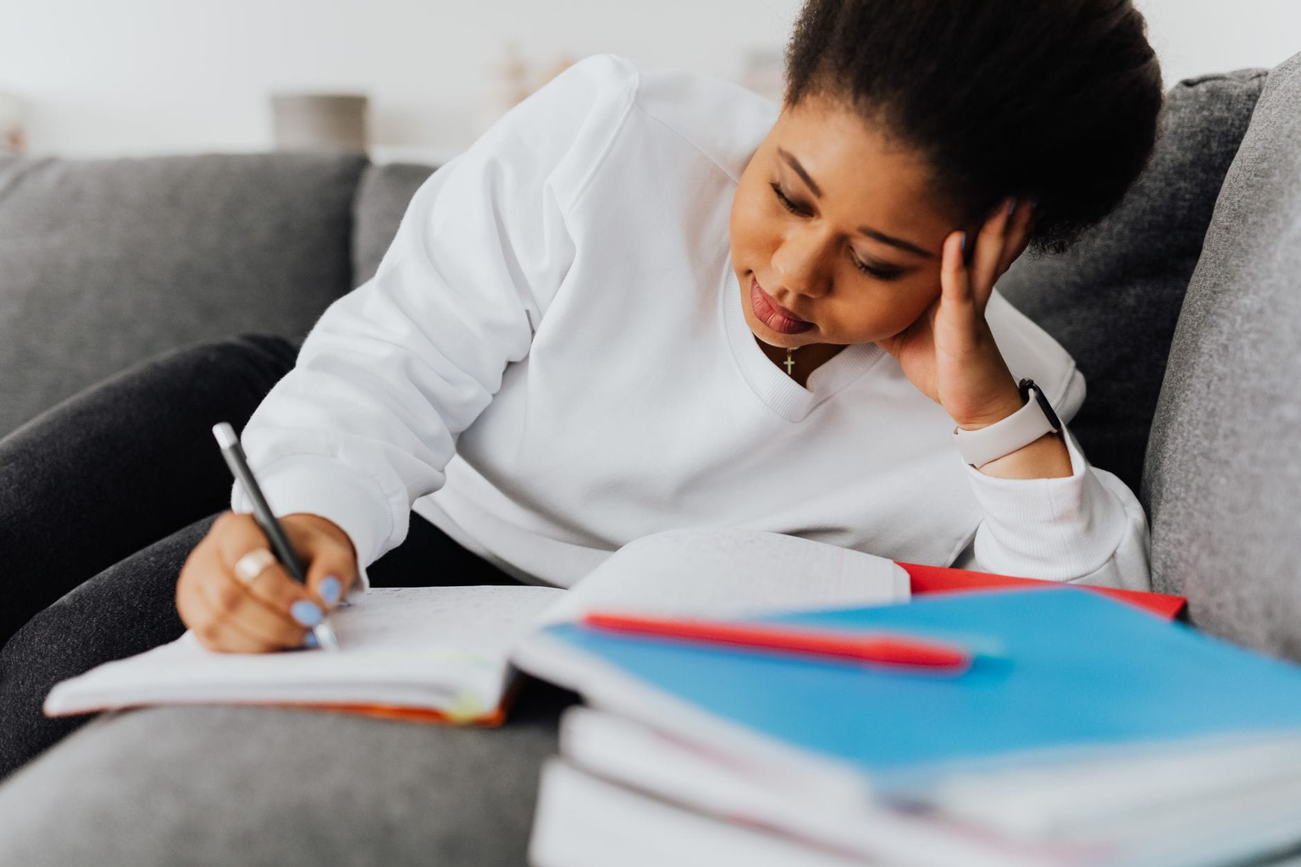 Studentka na kanapie uczy się z zeszytów i podręczników
